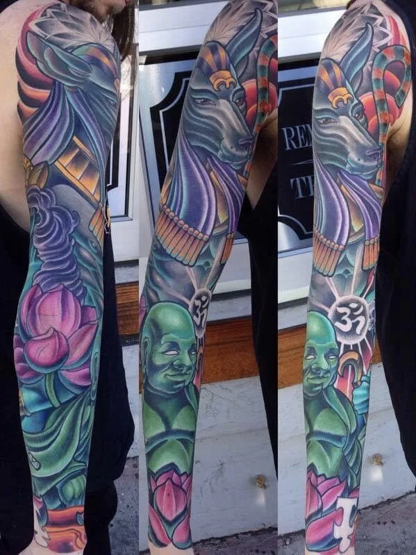 Full color arm sleeve tattoo of Anubis above a green Buddha with lotus flowers and an om symbol, shown from three angles by Terry Ribera at Remington Tattoo in San Diego.