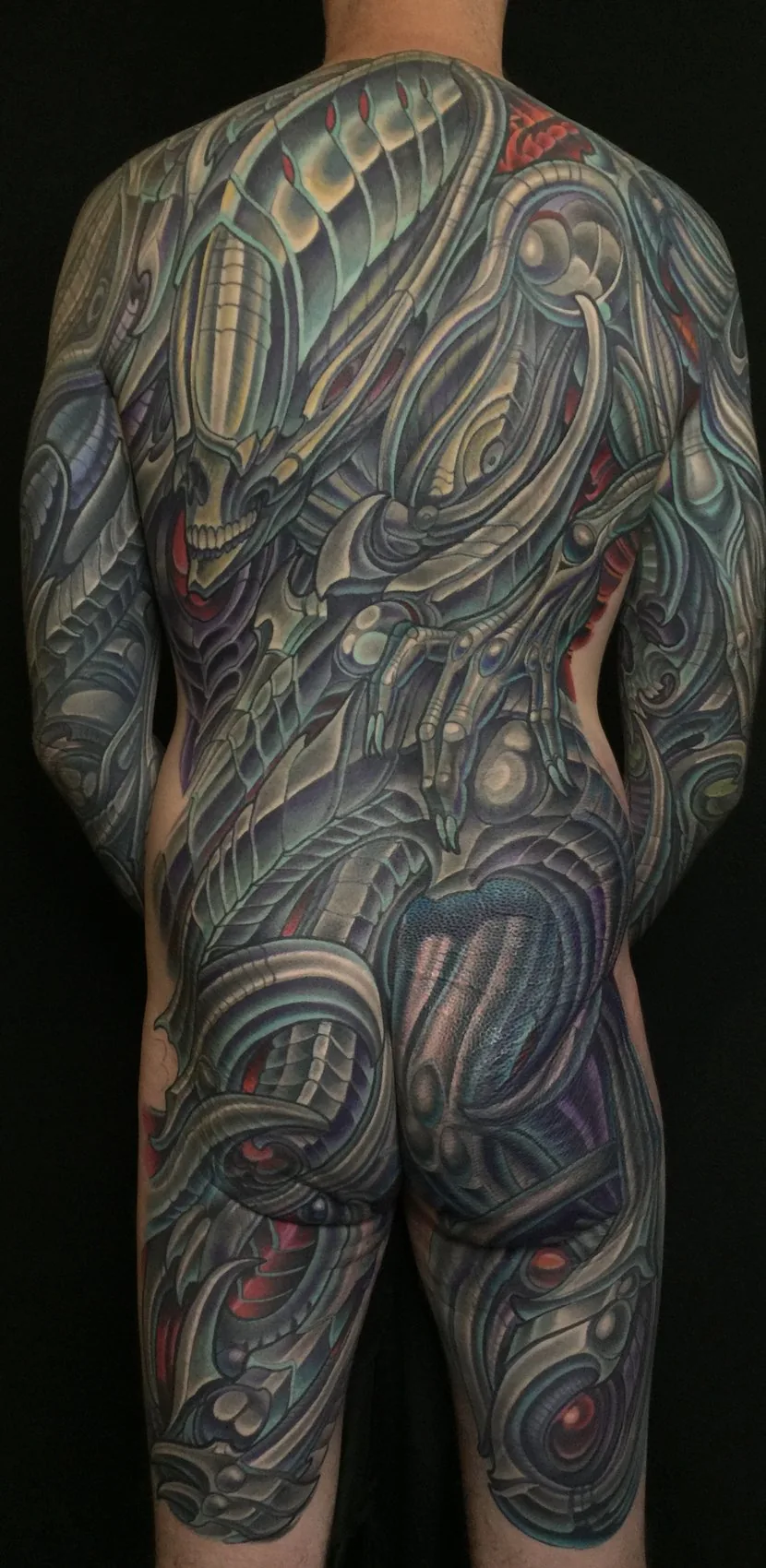 Biomechanical bodysuit tattoo, full rear view of the back, buttocks and thighs in continuous grey and teal biomech by Terry Ribera at Remington Tattoo in San Diego.