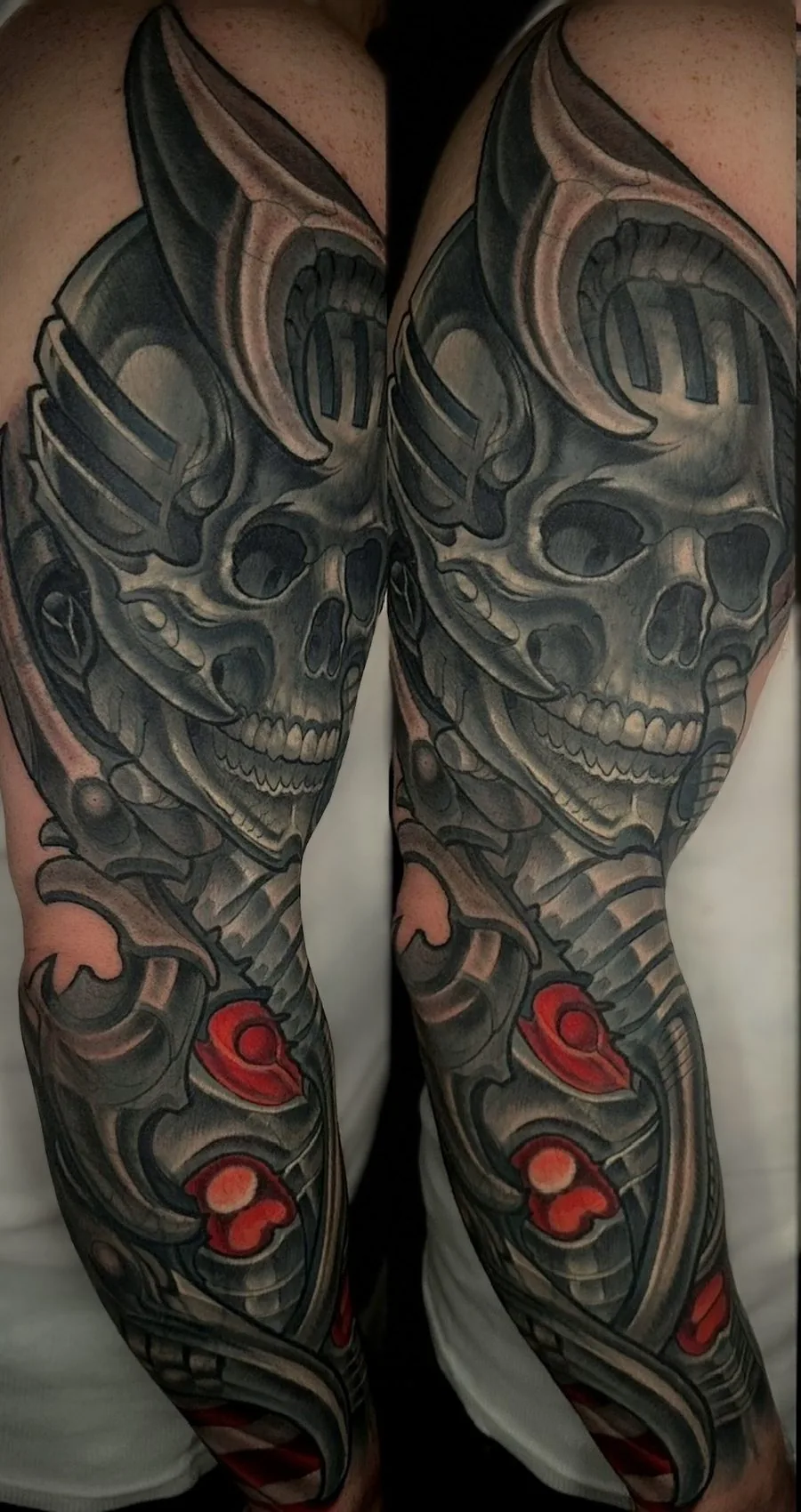 Black and grey biomechanical arm sleeve tattoo of a winged skull over mechanical structure with red accents, shown from two angles by Terry Ribera at Remington Tattoo in San Diego.