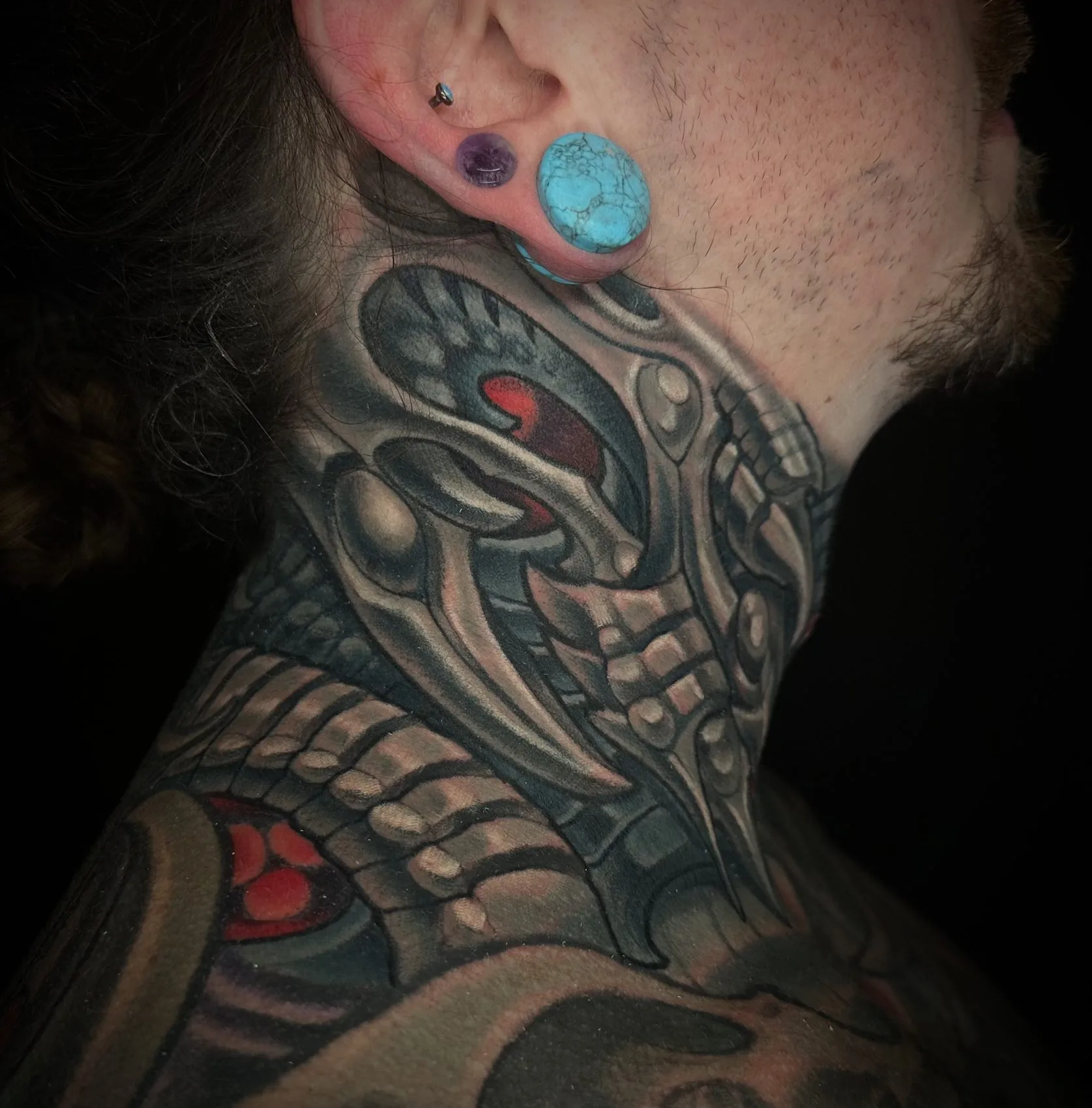 Left side view of the same biomechanical neck tattoo, wrapping behind the ear and down the side of the neck by Terry Ribera at Remington Tattoo in San Diego.