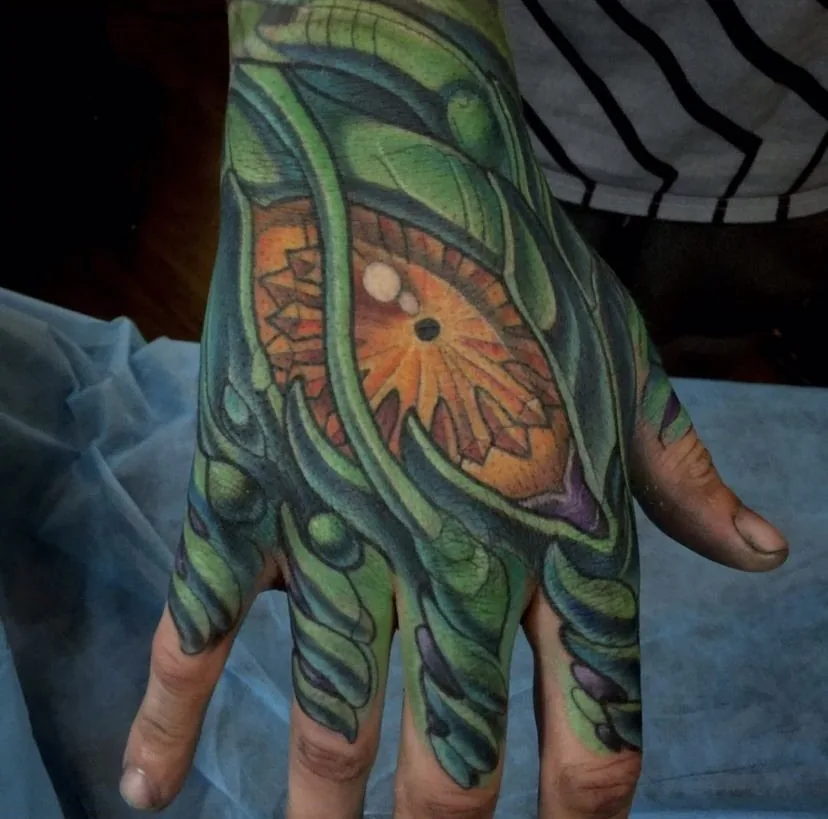 Biomechanical bodysuit tattoo, hand and fingers with an orange mandala on the back of the hand by Terry Ribera at Remington Tattoo in San Diego.