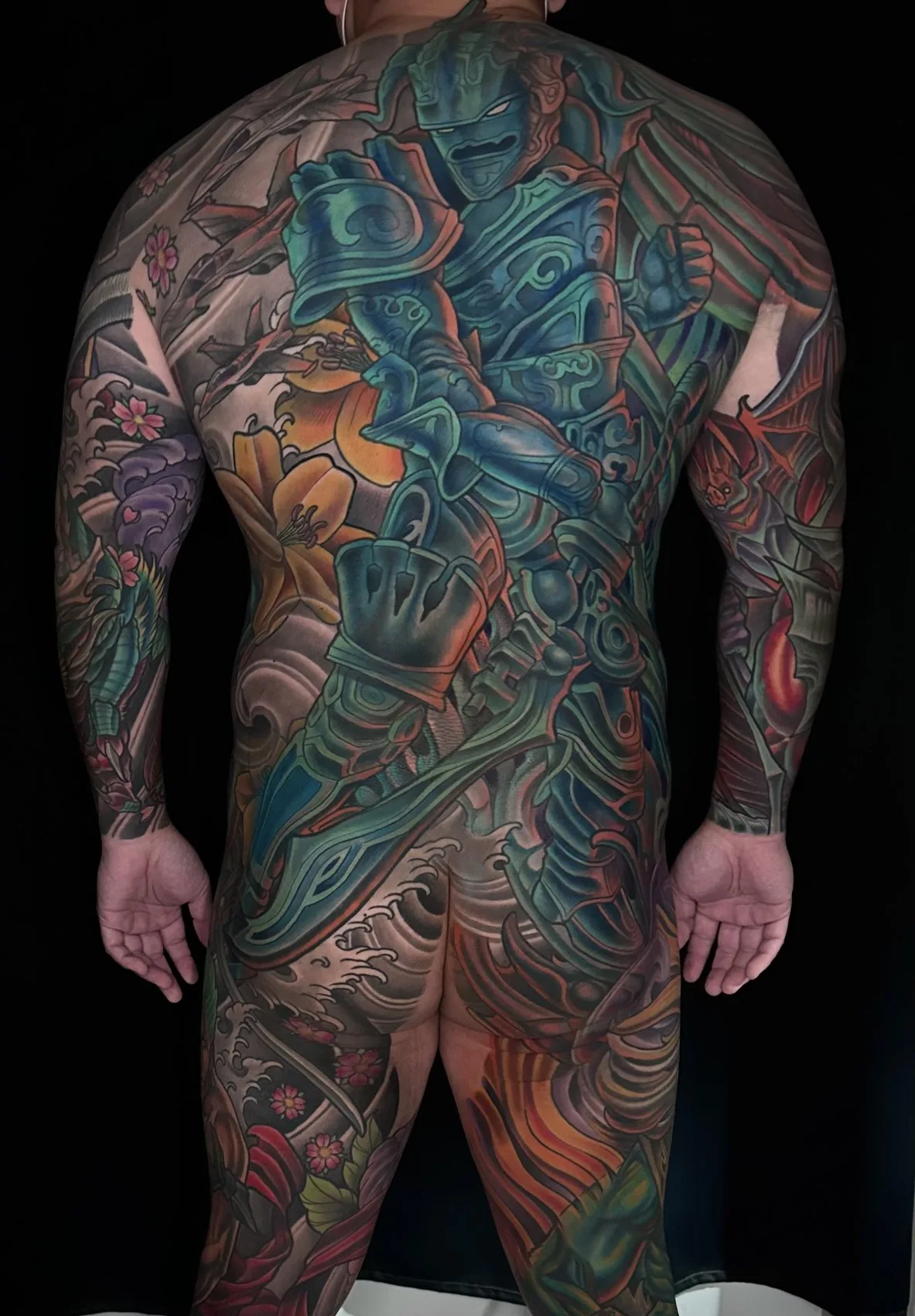Fantasy illustrative bodysuit tattoo, full rear view with an armored warrior back piece flowing into both leg sleeves by Terry Ribera at Remington Tattoo in San Diego.