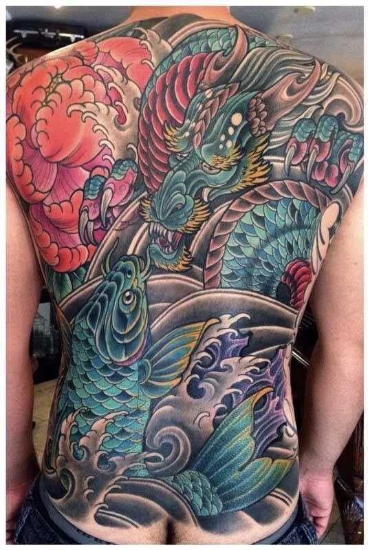 Neo Japanese full color back piece tattoo of a green dragon and koi among waves and clouds by Terry Ribera at Remington Tattoo in San Diego.