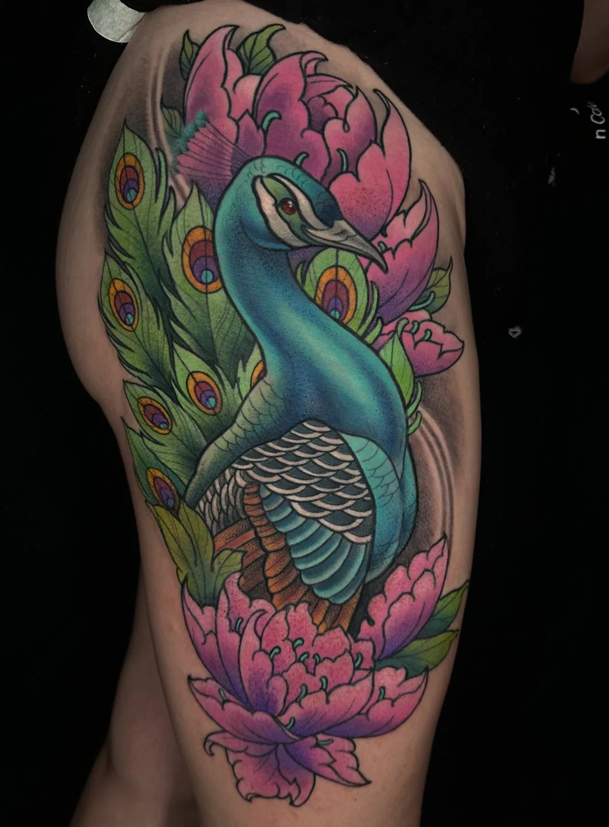 Neo traditional full color thigh tattoo of a peacock among pink peonies by Terry Ribera at Remington Tattoo in San Diego.