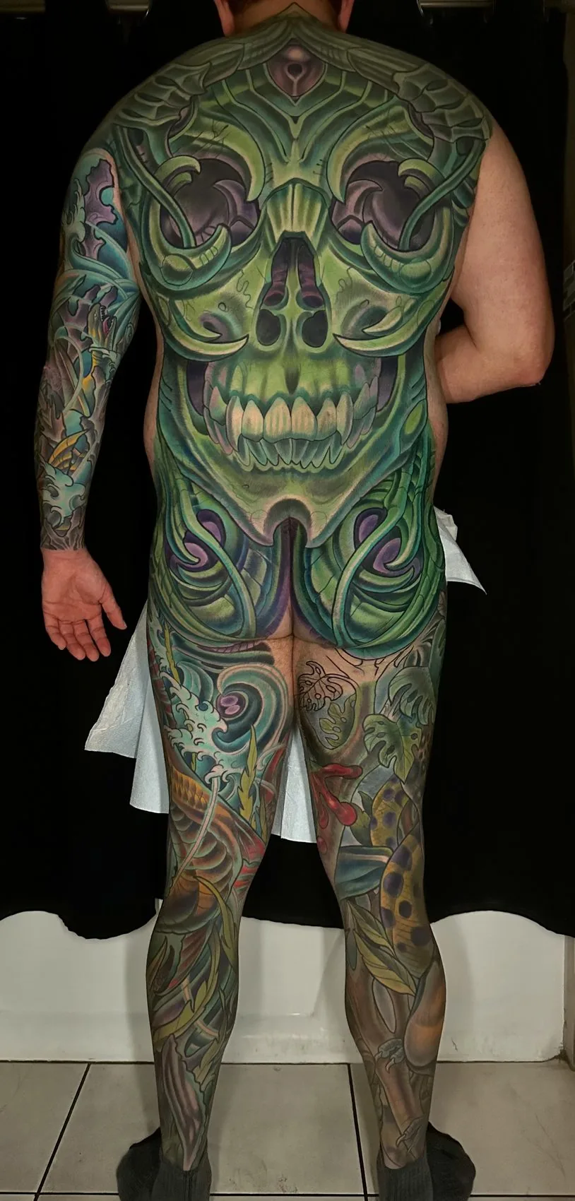 Illustrative wildlife bodysuit tattoo, full rear view of a bio-organic skull back piece continuing down into both leg sleeves by Terry Ribera at Remington Tattoo in San Diego.