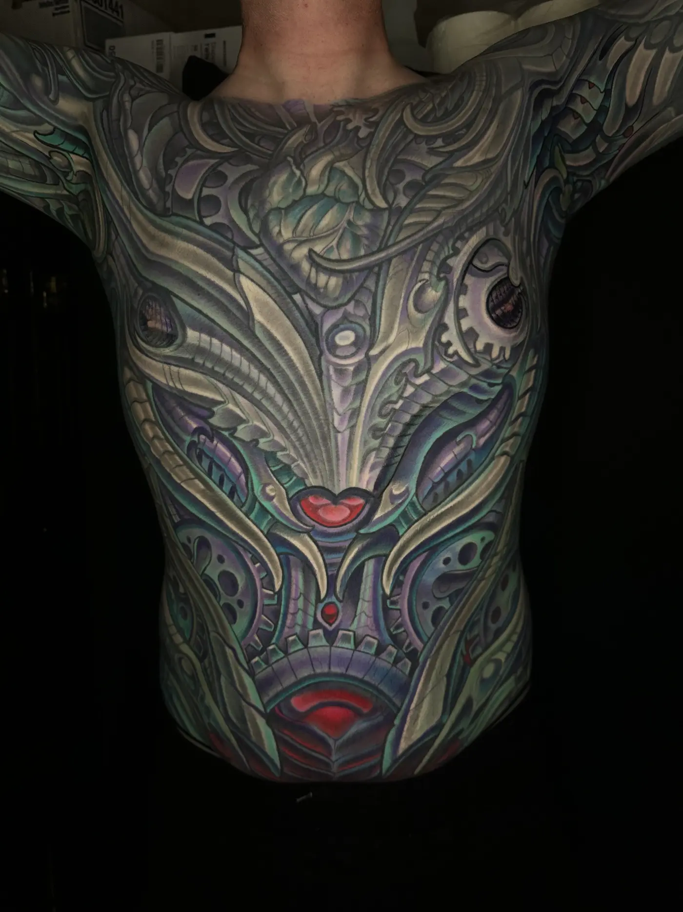 Biomechanical front torso tattoo in full color with layered mechanical and organic forms in purple and teal, by Terry Ribera San Diego