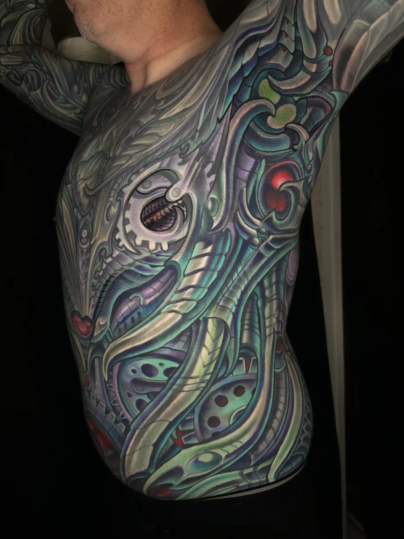 Biomechanical rib and side tattoo in color wrapping from chest to hip as part of a body suit, by Terry Ribera San Diego