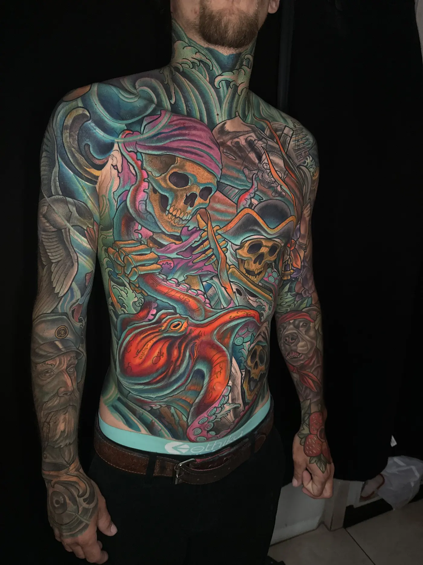 Front torso and neck tattoo in full color with skeleton pirates, a red octopus, and waves, large-scale custom work by Terry Ribera San Diego